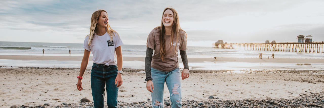 Two friends laughing together on a beach