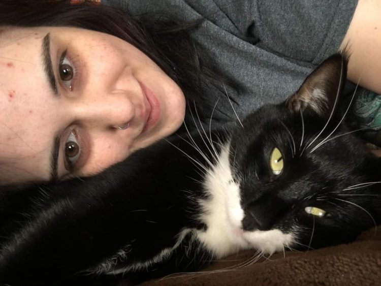 A woman cuddles with a black and white cat