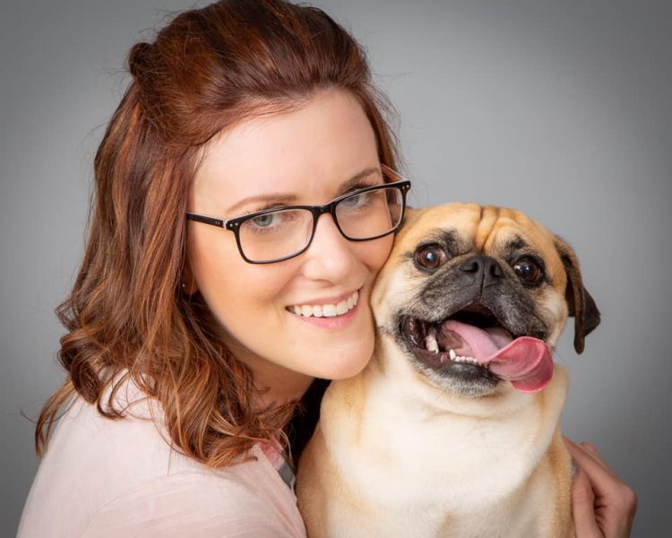 A woman cuddles with a pug
