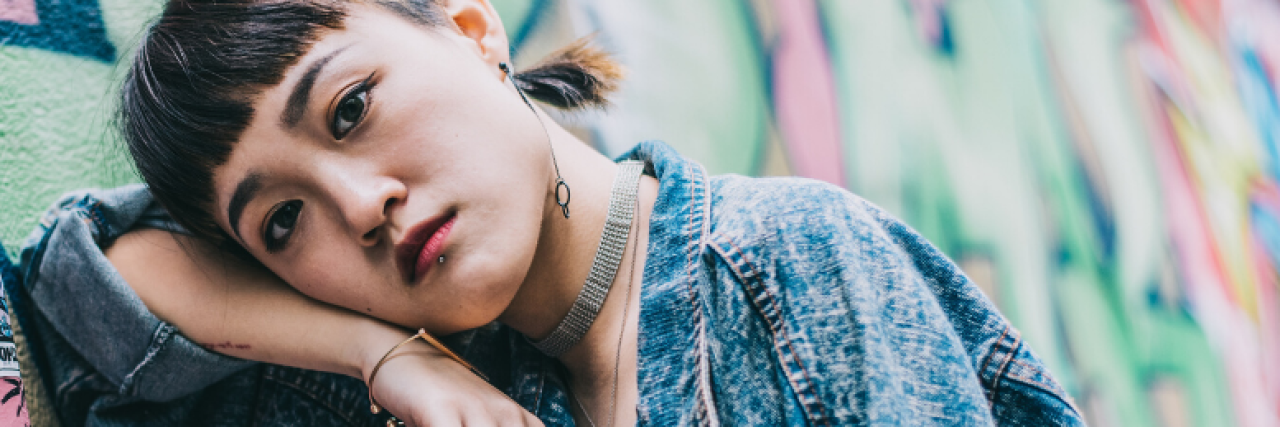 Borderline Personality Disorder: How People Avoid Abandonment A woman leaning against a colorful wall. Text reads: 6 ‘Frantic’ Things People With Borderline Personality Disorder Have Done to Avoid Abandonment