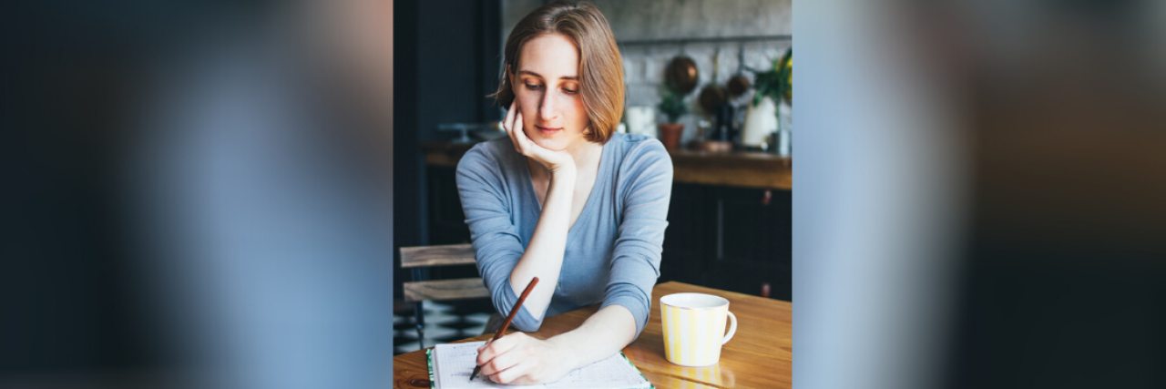 The Struggle of Surviving Childhood Cancer Young woman writing in a notebook at home