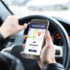 Rideshare driver in car using app.