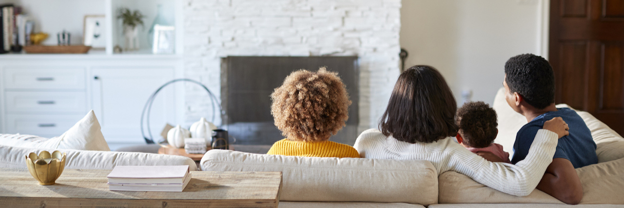 Letting Go of Unrealistic Parenting Expectations During COVID-19 Back view of a diverse family sitting and watching TV together