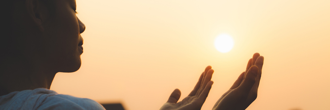 How the Church Can Better Support People Who Are Hurting Woman praying in the morning on the sunrise background.
