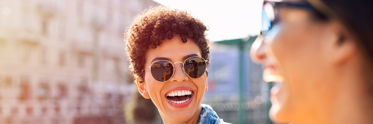 18 Things to Do (and Not Do) When Someone Tells You They Have Epilepsy Woman of color wearing sunglasses and smiling at friend outside