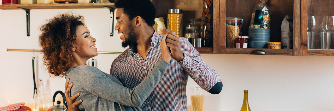Young African-American couple dancing in kitchen