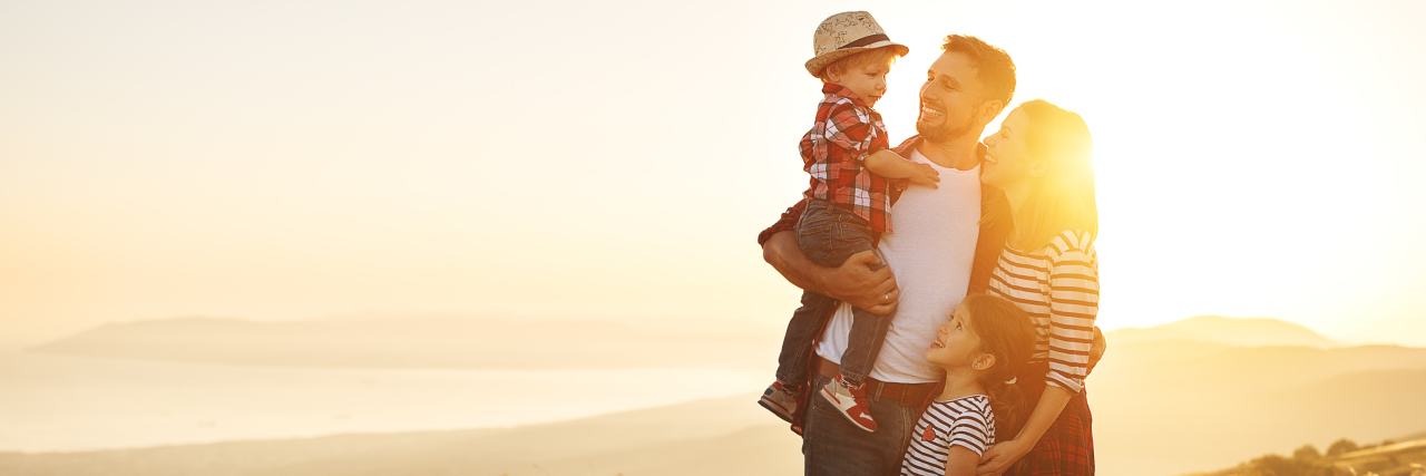 10 Ways to Support Parents of Kids With Disabilities Happy family in a field at sunset.