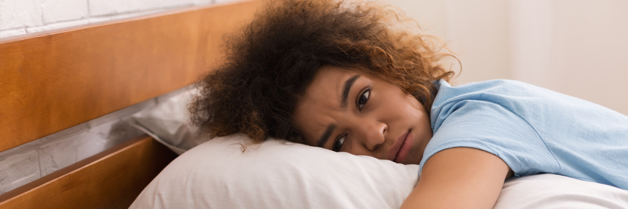 Let's Talk About Living With Painsomnia Woman with painsomnia trying to sleep.