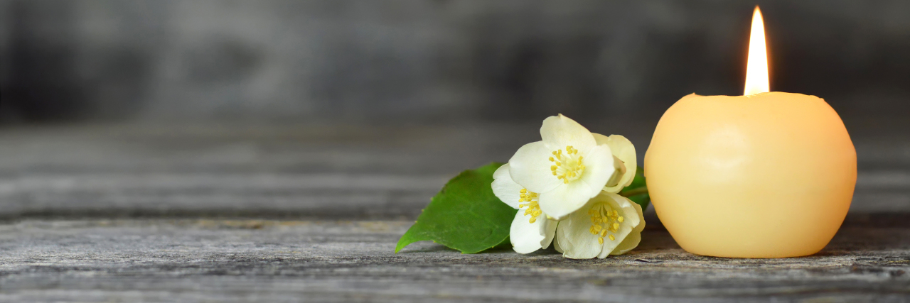 The Down Syndrome Community Is Mourning the Deaths of 3 Children a white candle and a white flower