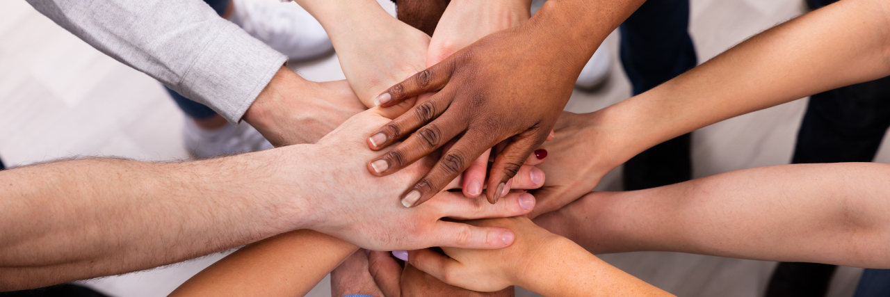 Diverse people putting hands together.