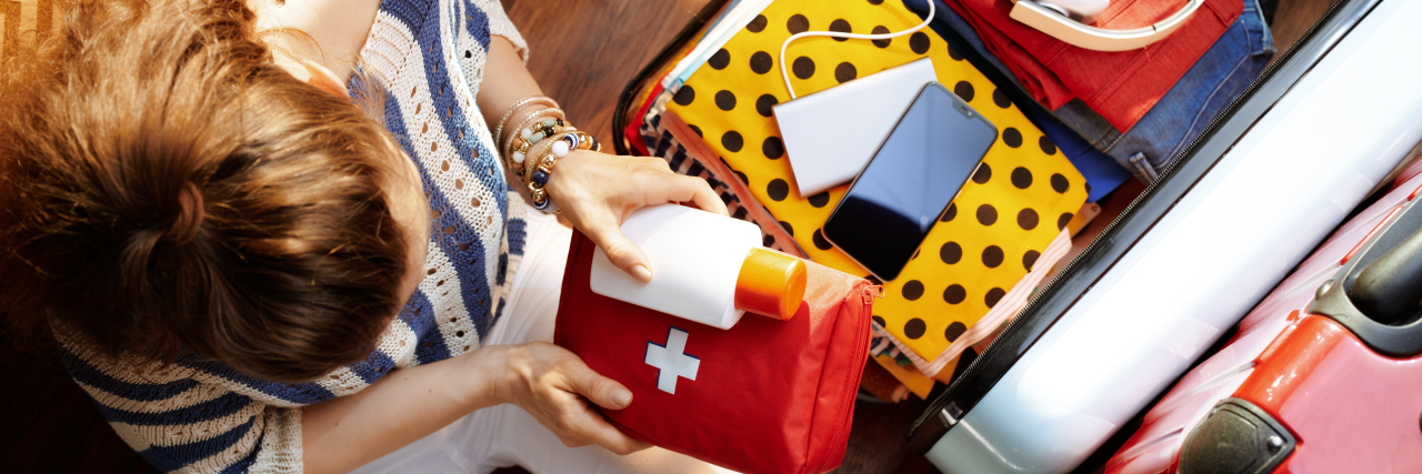 Woman packing first aid kit for travel.