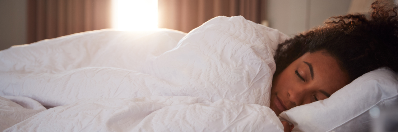 The Importance of Sleep Hygiene in Life With Hypersomnia Woman sleeping in bed.