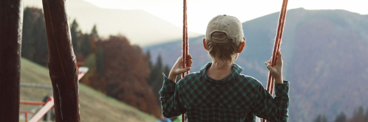Managing Sensory Needs in Kids With Disabilities During COVID-19 Boy on a swing looking at mountains.