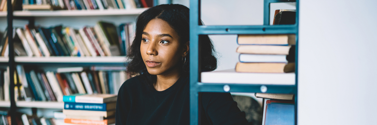 Mental Health Tips for Incoming College Freshman Image of a Black woman reading near a bookshelf