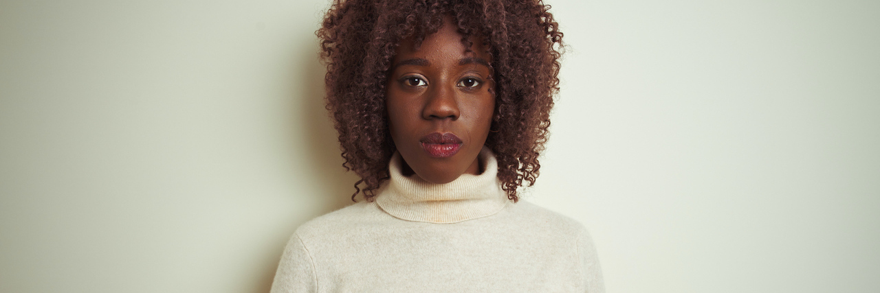The Difference Between Feeling Anxious and Having an Anxiety Disorder A woman sitting against a blank backdrop with a serious expression on her face
