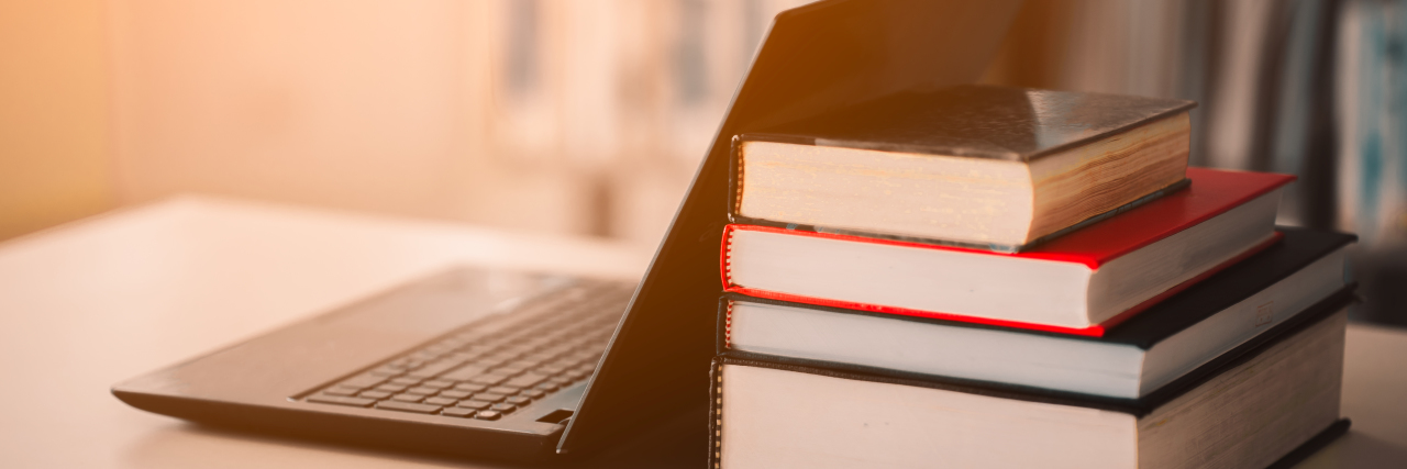 Staying on Lockdown During COVID-19 as a Teacher With Chronic Illness Laptop and books.