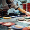 A chef putting a place down on conveyor belt sushi
