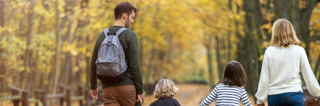 Deciding Whether to Have Children as Someone With a Genetic Condition Family holding hands outdoors.