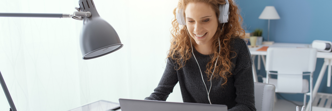 Young woman wearing headphones taking online class.