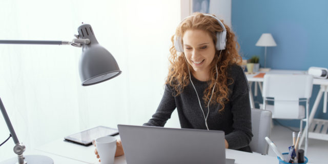 Young woman wearing headphones taking online class.