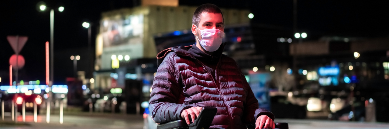 Why Disability Advocacy Matters During COVID-19 Disabled Caucasian man sitting on wheelchair wearing medical face mask for coronavirus protection.
