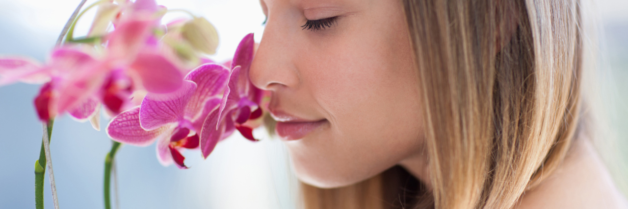 How to Change the Way You View Yourself and Your Mental Illness photo of woman smelling a pink orchid