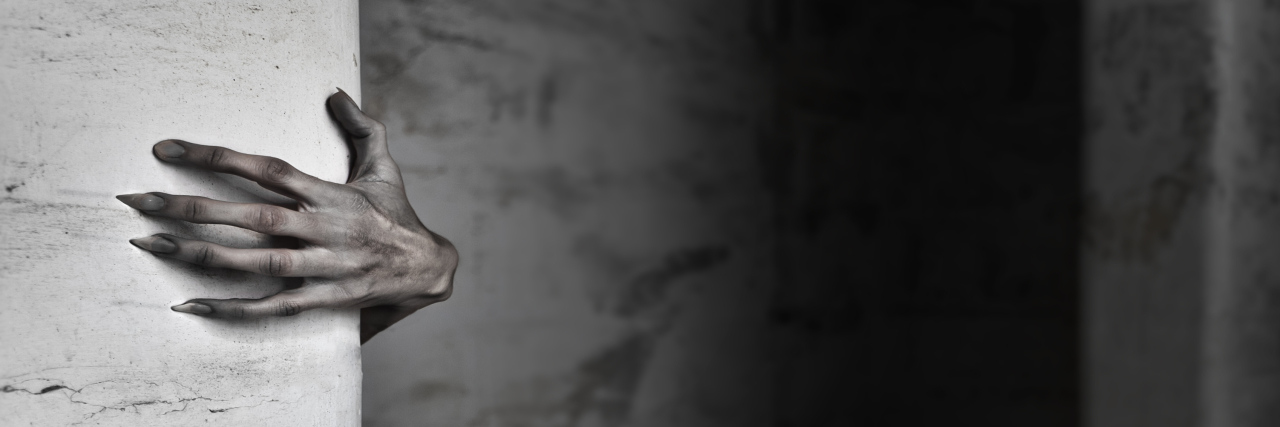 My Response to JK Rowling as a Queer Autistic A spooky female hand protruding from behind a wall.