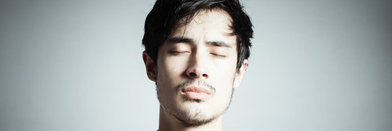 How I Explain Tardive Dyskinesia to Others Man blinking his eyes due to tardive dyskinesia.