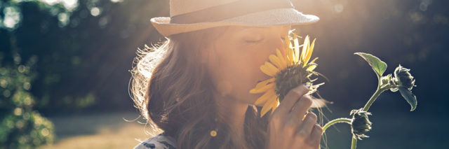 Woman smelling sunflower.