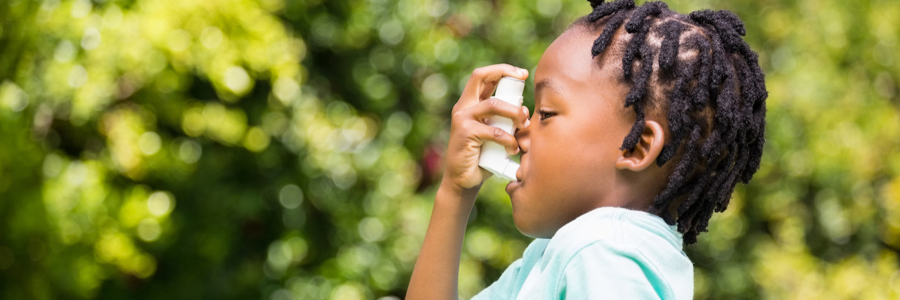 Study: Kids With Developmental Disabilities More Likely to Have Asthma Black boy using an asthma inhaler in the park