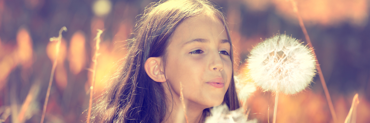 Outdoor Activities to Enjoy With Your Child With a Disability Girl blowing dandelion seeds.