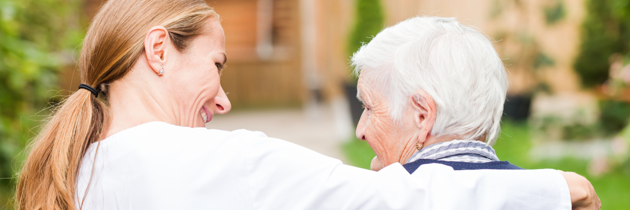 Why I Felt Closer to My Mom With Alzheimer's When She Didn't Know Me a woman has her arm around an elderly woman sitting outside