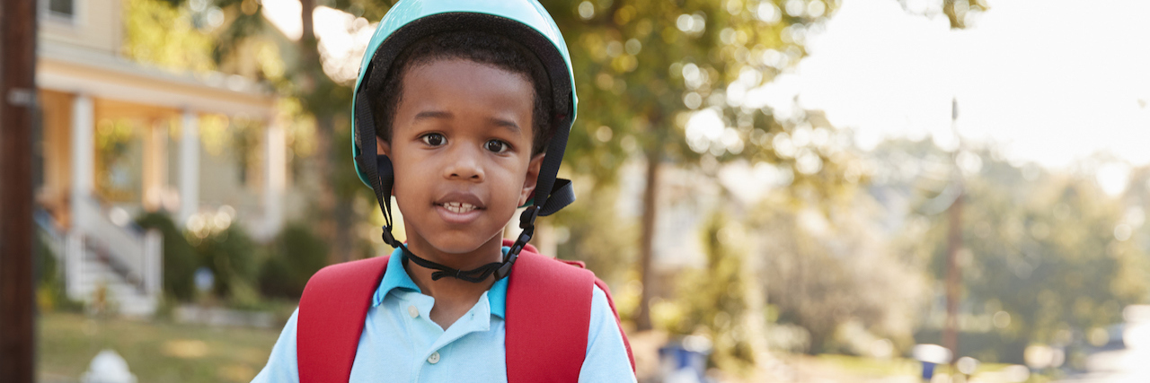 Tips for Helping Your Black Autistic Son Interact With Police A young boy on a scooter wearing a helmet
