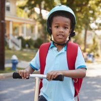 A young boy on a scooter wearing a helmet