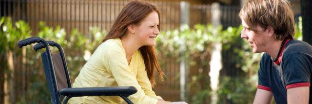 Young woman in wheelchair with male friend.