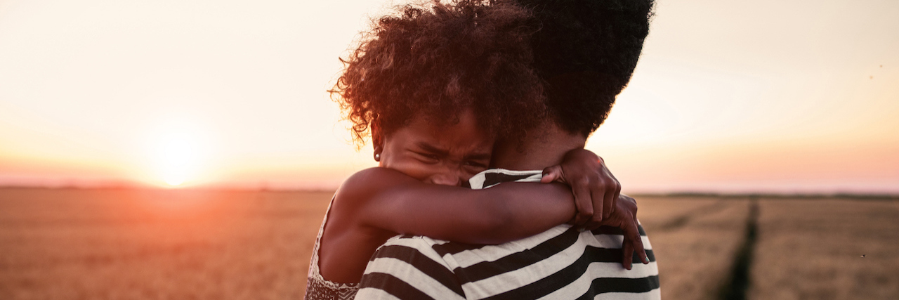 A father holding his daughter outside as the sun is setting