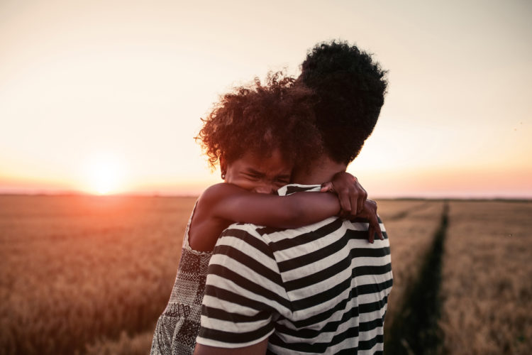 A father holding his daughter outside as the sun is setting