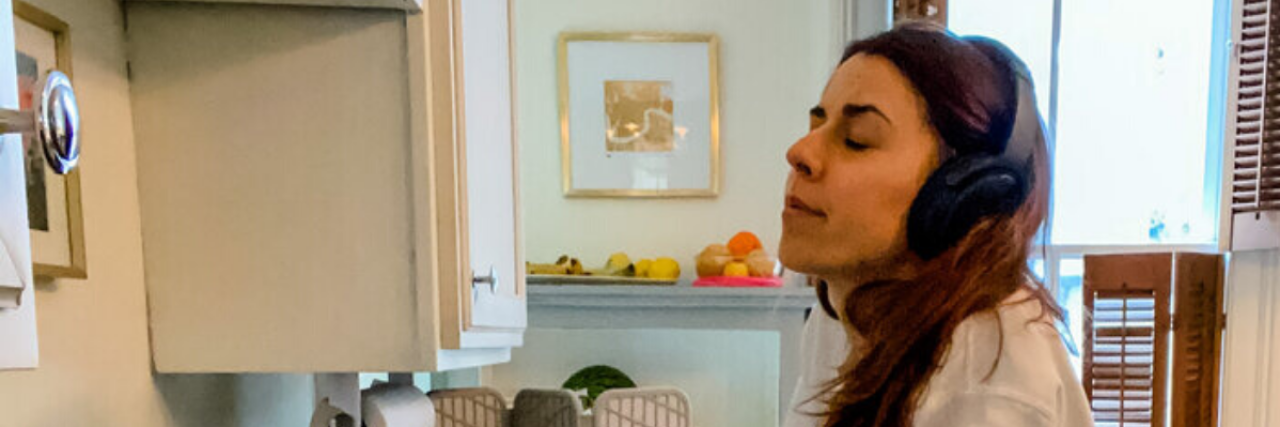 Tips for 'Feeling Your Feelings' With Kindness and Self-Care photo of woman resting her hands on a sink, wearing headphones and listening to music with her eyes closed