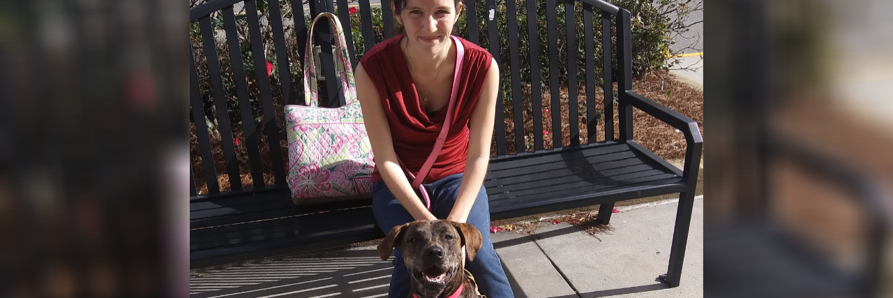 photo of contributor siting on a bench and holding her service dog