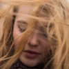 A woman with windswept hair in her face