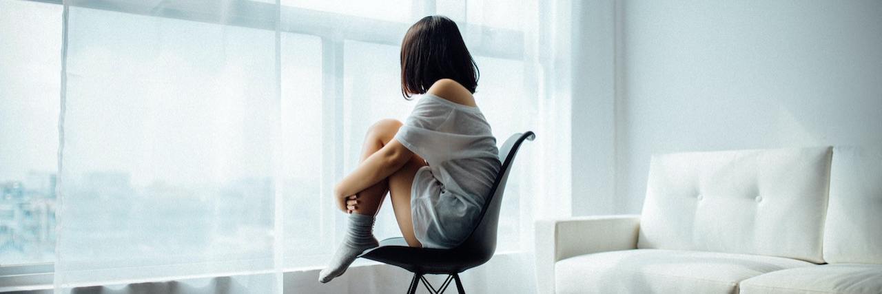 Study Suggests Self-Image Is Related to Feelings of Loneliness Lonely woman with short dark hair sitting in a chair looking out the window