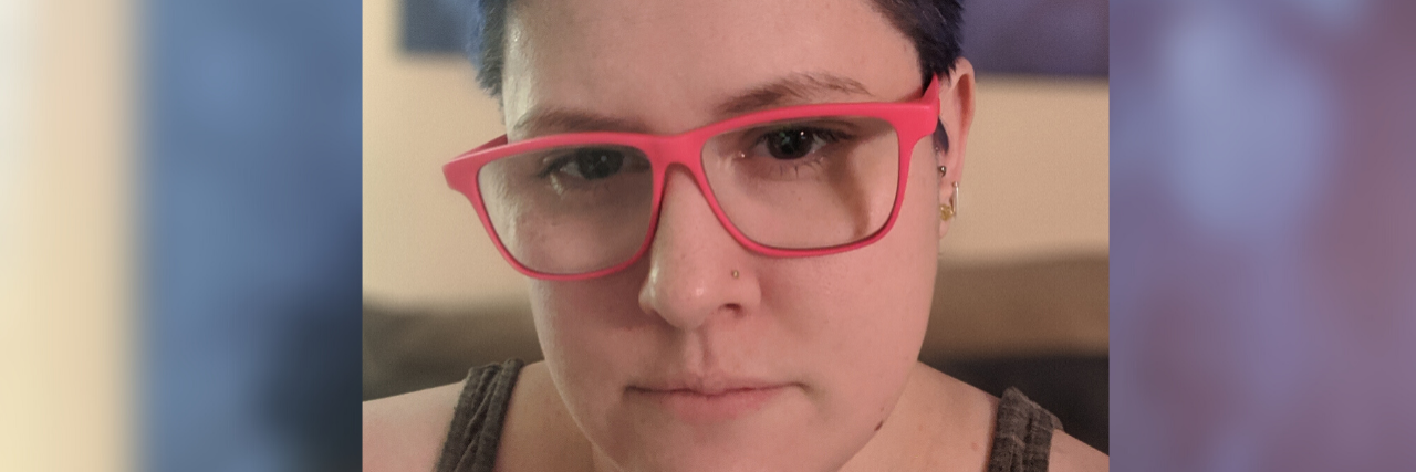 Living at the Intersection of Queerness, Neurodiversity and Disability Cole wearing a black tank top and red glasses.