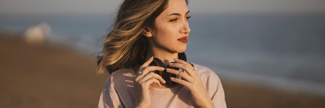 Relatable Letter to an Abusive Father When Healing From Trauma photo of woman standing on beach in sunset light, looking hopeful