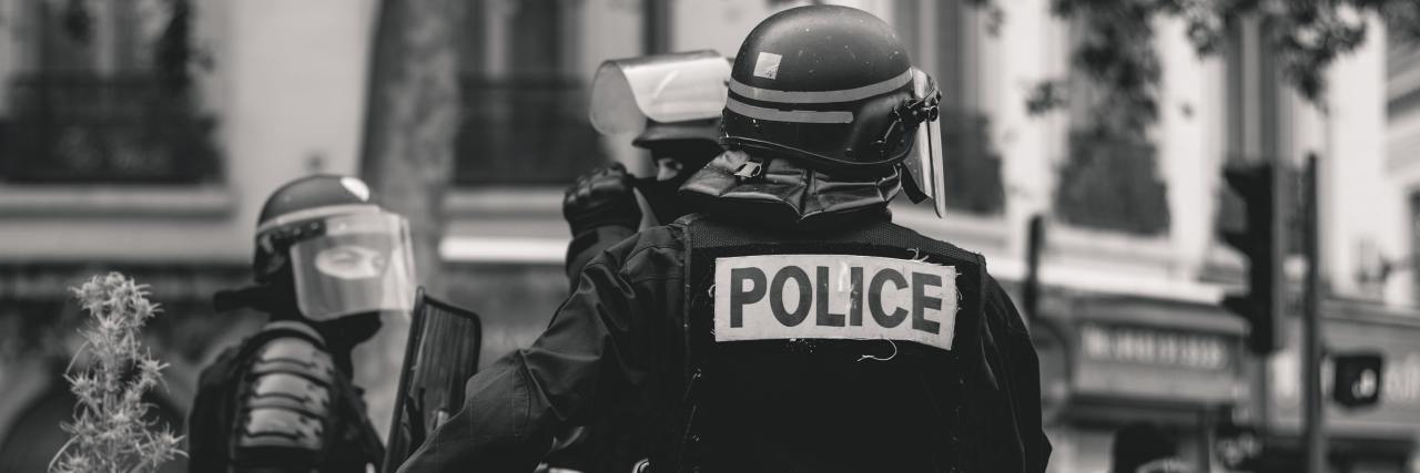 Cop Who Killed Disabled Man at Costco Faces Job Review Black and white photo of a police officer from the back