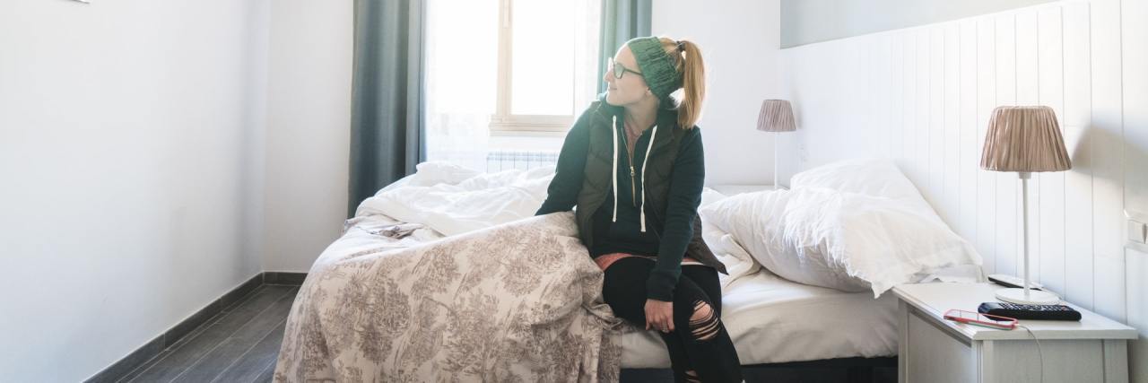 Silver Linings to Chronic Illness Life photo of woman sitting on bed in a brightly lit room