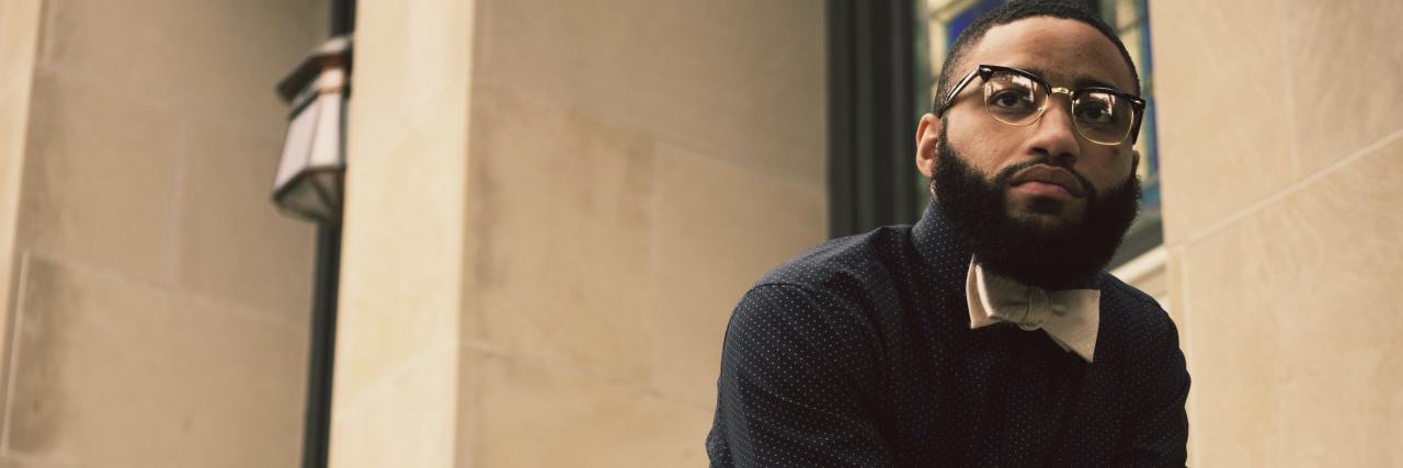 Black Lives Matter: Why Violent Footage of Murders Can Cause PTSD photo of man leaning on railing on some steps, wearing a bow tie and looking into the distance