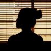 photo of woman silhouetted in front of window blinds