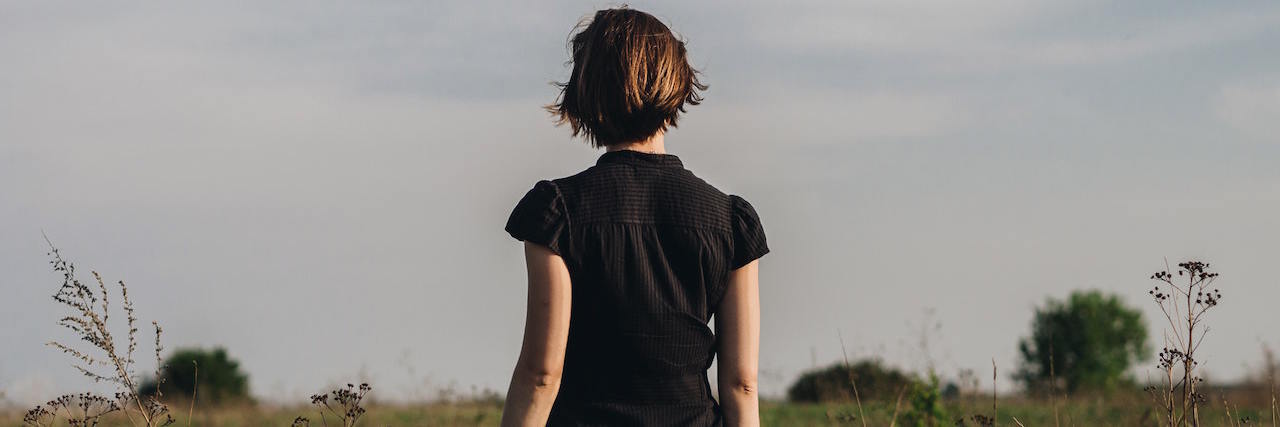 The Importance of Acknowledging My Mental Illness Woman with short hair facing away from camera and looking at landscape