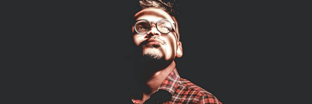 Positive Effects the Coronavirus Pandemic Has Had on My Mental Health photo of man standing in darkness with a bright light overhead, looking up into it