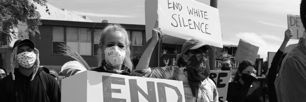 black and white photo from Black Lives Matter protest, showing white people holding signs that say "end white silence"